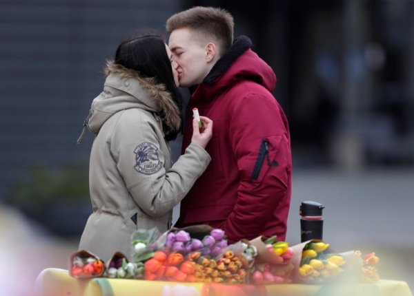Двойка се целува пред маса за продажба на цвета в Минск ден преди 8 март. Снимка: БТА