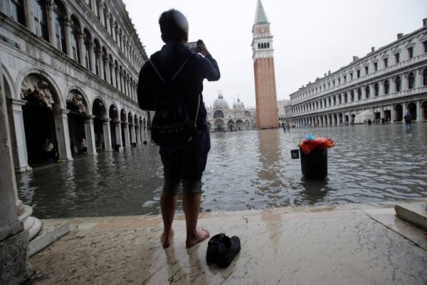 Мъж прави снимки на наводнения площад Сан Марко във Венеция. Снимка: БТА