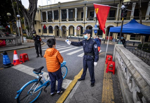 Полицай мери температурата на дете на импровизиран пропускателен пункт в китайския град Гуанджоу. В най-многолюдната страна продължават безпрецедентните мерки във връзка с коронавируса. Снимка: БГНЕС