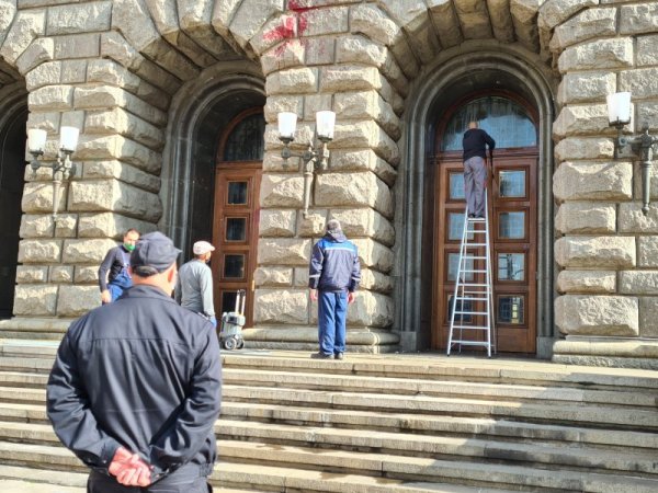 Работници почистват фасадата на сградата на Народното събрание, която от месеци стои със следи от червена боя и яйца хвърляни по време на по-масовите антиправителствени протести. Снимка: БГНЕС