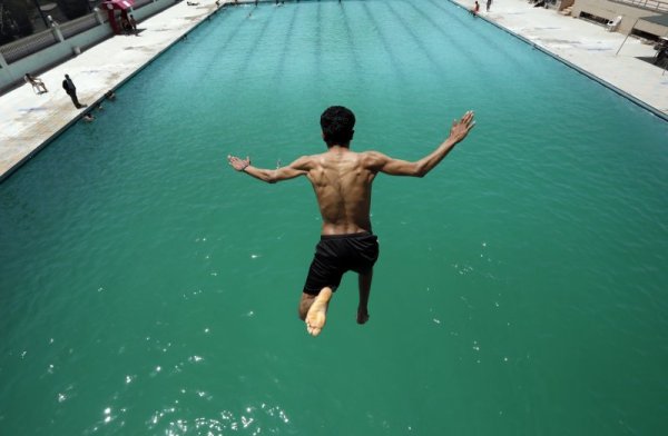 Мъж скача в басейн, за да се разхлади от летните жеги в Йемен. Снимка: БГНЕС