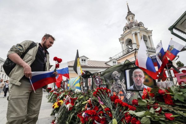 Млад мъж с руското знаме в ръка слага цветя пред импровизиран кът за прощаване с лидера на Вагнер Евгени Пригожин в Москва. Пригожин загина в самолетна катастрофа през август няколко месеца след похода му към руската столица. Снимка: БГНЕС